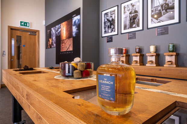 Bottle of Hebrach whisky on a wooden counter with framed pictures on the wall.