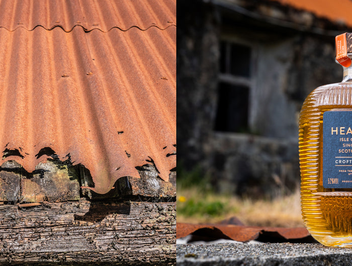 Bottle of Hearach whisky on a rustic background with a corrugated metal roof.