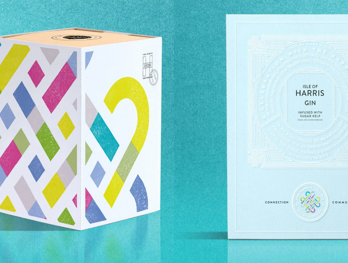Colorful box with geometric patterns, a white box, and a pink bottle on a teal background