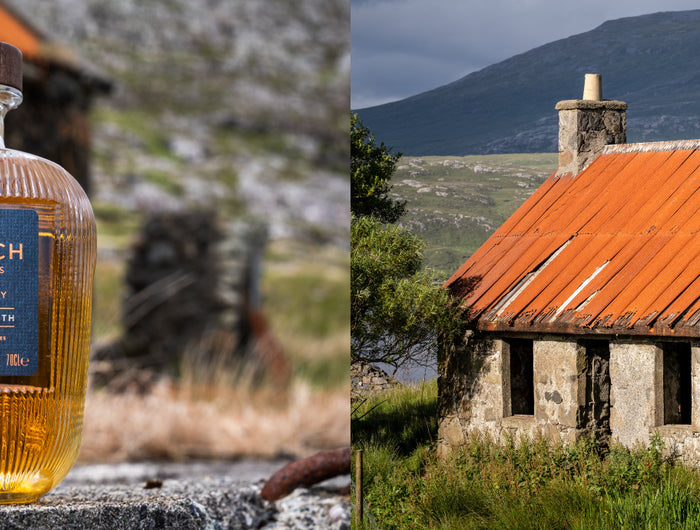 Bottle of The Hearach whisky with a scenic background of a stone building and mountains.